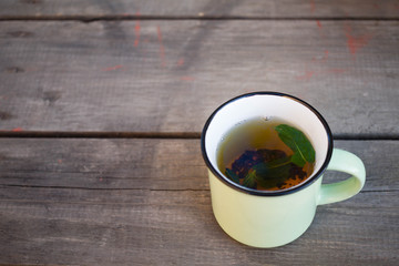 tea with mint in a green mug on a wooden background