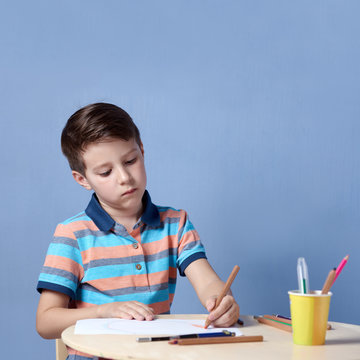 European boy spending time drawing with colorful pencils at home.