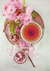 Obraz na płótnie Canvas vintage, antique cup of fruit tea decorated with cherry flowers on white background in a shabby chic look