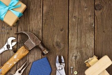 Fathers Day theme corner border of gifts, tie and tools on a rustic wood background. Top view with copy space.