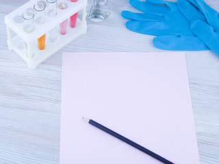 record diagnosis, medical report: the pink sheet of blank paper and red pen on it, around in selective focus, test tube, flask, gloves of a medical expert, in blue light