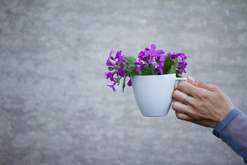 a cup of flowers with a girl in her hand