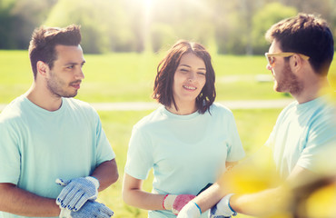 volunteering, charity, people and ecology concept - group of happy volunteers in park