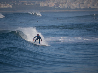 Surfer surfing waves at costa da caparica, nearby the city of lisbon