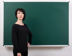 girl teacher posing by chalk Board, learning concept, green background, Studio shot