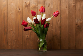 bouquet of tulips in a vase, wooden background
