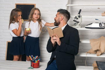 Teacher man read story to girls eating apple. School time of sisters and father in library. Education in knowledge day. Literature lesson and reading grammar book. Back to school and home schooling