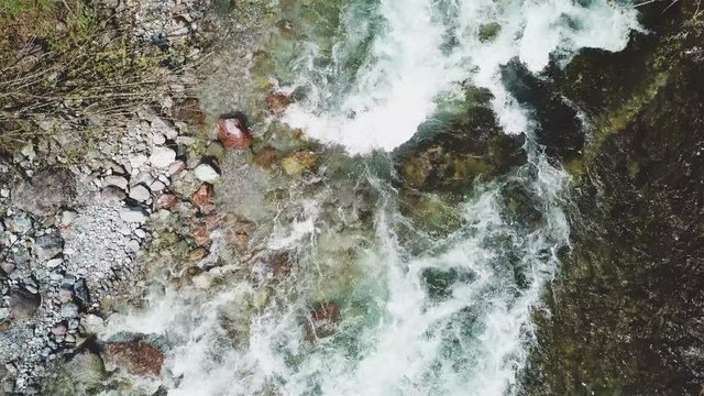flying over a stream and waterfalls in mountains - aerial top view shot from 4k drone

