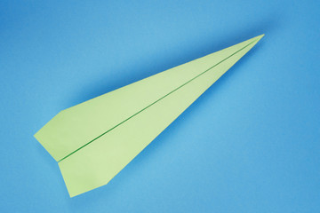 Green paper plane on blue