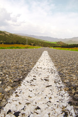 Close up White Road Strip. Road Surrounded by Green Fields. 