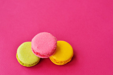 Fototapeta na wymiar three macaroons on a pink background with a place under the text
