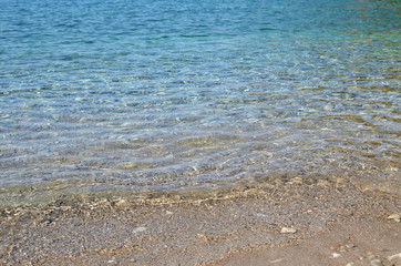 Blue sea water, small wave and wet sand of a beach