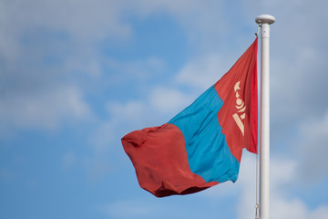 Naklejka na ściany i meble national flag of mongolia blowing in the wind with blue sky in background
