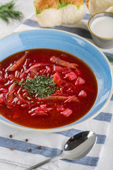 Fresh Ukrainian Russian vegetable borscht in a plate. On a table with a napkin. Top view