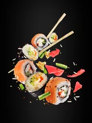 Cercles muraux Bar à sushi Différents rouleaux de sushi frais avec des baguettes congelées dans l& 39 air sur fond noir