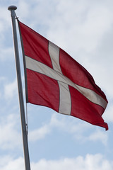 national flag of Denmark blowing in the wind with blue sky and clouds  in background