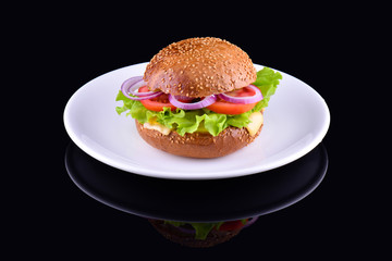 Fresh tasty burger isolated on black background. Tasty and appetizing cheeseburger on white plate. Vegetarian burger