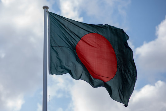 national flag of Bangladesh blowing in the wind with blue sky in background