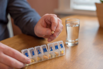 Filling a pill organizer with daily supplements and vitamins