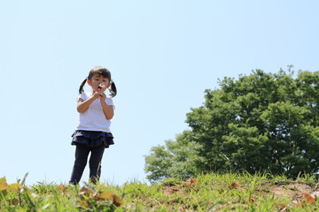 Obraz premium タンポポを吹く幼児(3歳児)と青空
