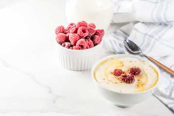 Healthy breakfast, semolina porridge with milk and raspberry, white marble table copy space