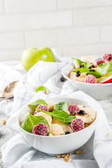 Healthy summer breakfast, fruit and berry salad with spinach, granola, apple and banana, white marble background  copy space