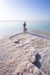 Blonde young  woman in a long skirt on the shore of the dead sea. Jordan