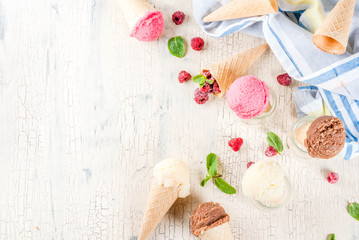 Summer sweet berries and desserts, various of ice cream flavor in cones pink (raspberry), vanilla and chocolate with mint on light concrete background copy space top view