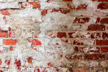 texture of an old wall of an ancient building with a ruined plaster layer and cracked red bricks, abstract background