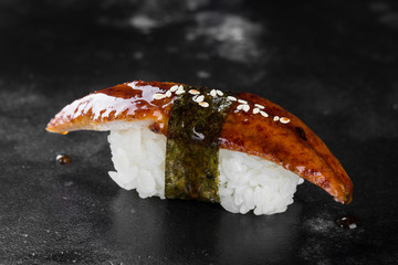 Sushi nigiri with eel on black background with reflection