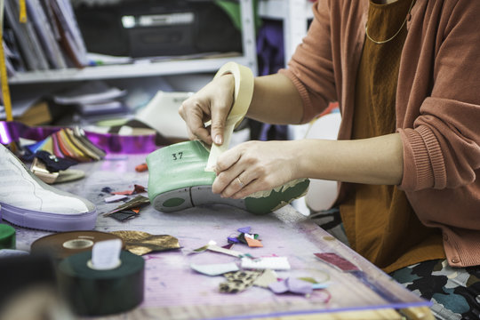 Woman designer making handmade shoes in her workshop