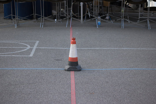Separating strips and sign of stop are on an asphalt before the start of an event. In the background there is a lower part of music stands. It`s quiet and nobody around before a concert on a street.