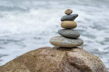 Fototapeta na wymiar Stacked Stones on top of a huge stone in the ocean
