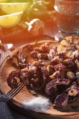 Grilled octopus tentacles on fork on rustic plate close view