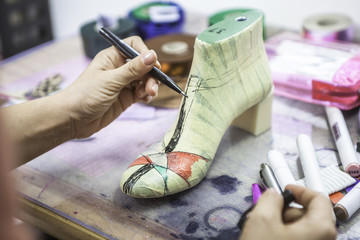 Woman designer making handmade shoes in her workshop