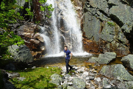 A man standing near waterfall.