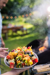 In summer. A couple prepares a bbq to welcome friends in the garden. Close-up on a plate of grill...