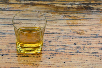 Old, good plum brandy in glass on grunge wooden table