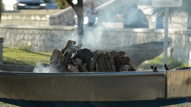 Barbecue with wooden logs burning in a bonfire or campfire at sunset
