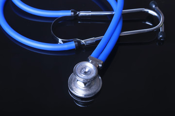 stethoscope, Red heart on black mirror background. Selective focus.