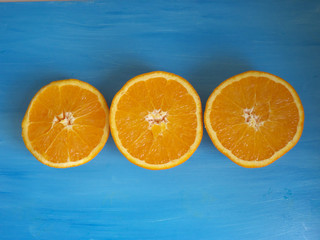 Tres naranjas cortadas por la mitad sobre un fondo azul