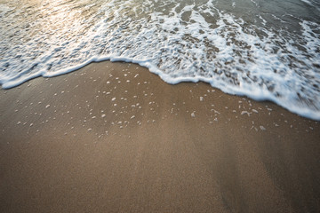 Wave on the sand when Sunset background.