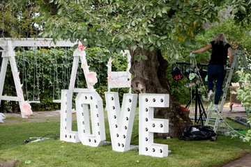Large letters LOVE with bulbs stand on a green lawn. Wedding Decor LOVE