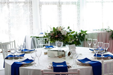 Beautiful table setting with a white tablecloth and blue napkins