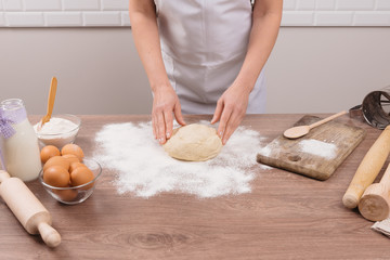 Female hands making dough for pizza. Woman kneading dough on table, closeup.