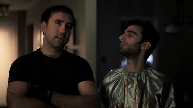 Two men examine and discuss artwork in a dark room.