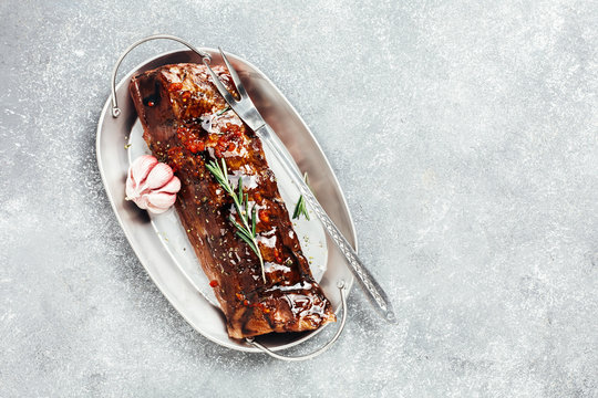 Uncooked pork ribs in a marinade with spices on a baking tray