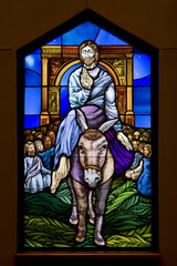 Jesus entering Jerusalem on donkey Bible depiction on stain glass 