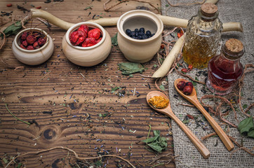 Alternative herbal medicine concept. Different wild berries and other organic ingredients on brown wooden table surface.