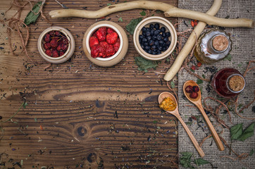 Fototapeta na wymiar Alternative herbal medicine concept. Different wild berries and other organic ingredients on brown wooden table surface.